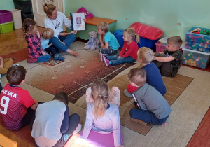 Na zdjęciu: dzieci siedzące na dywanie w klasie oglądają Dzienniczek lektur założony do programu " Mały Miś w świecie wielkiej literatury" dzieci siedzące na dywanie w klasie słuchają nauczycielki czytającej książkę